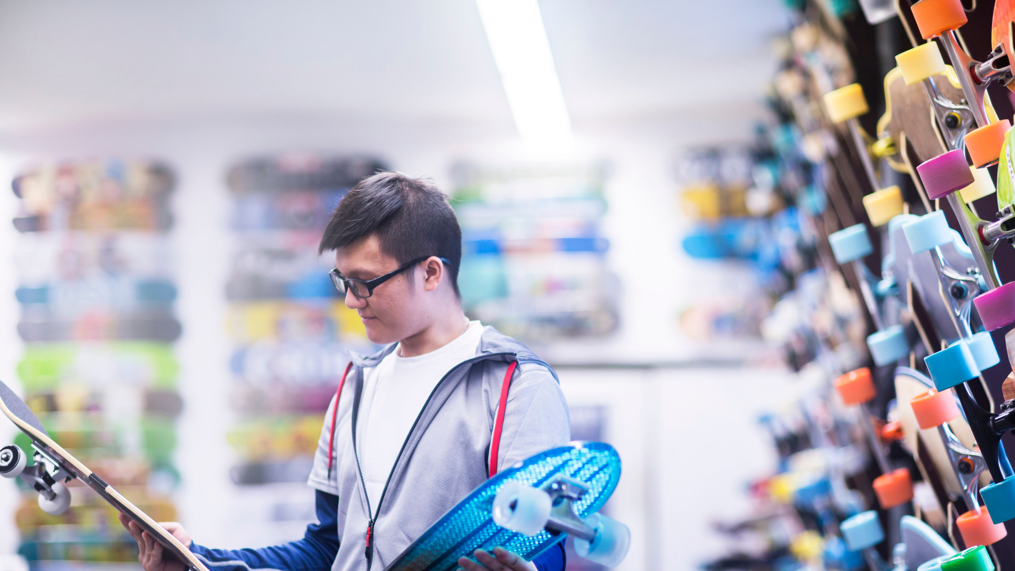 Young male skateboarder looking at skateboards 